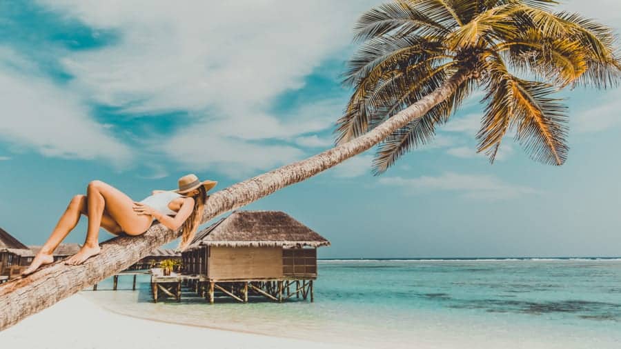 Woman laying on palm tree, Maldives