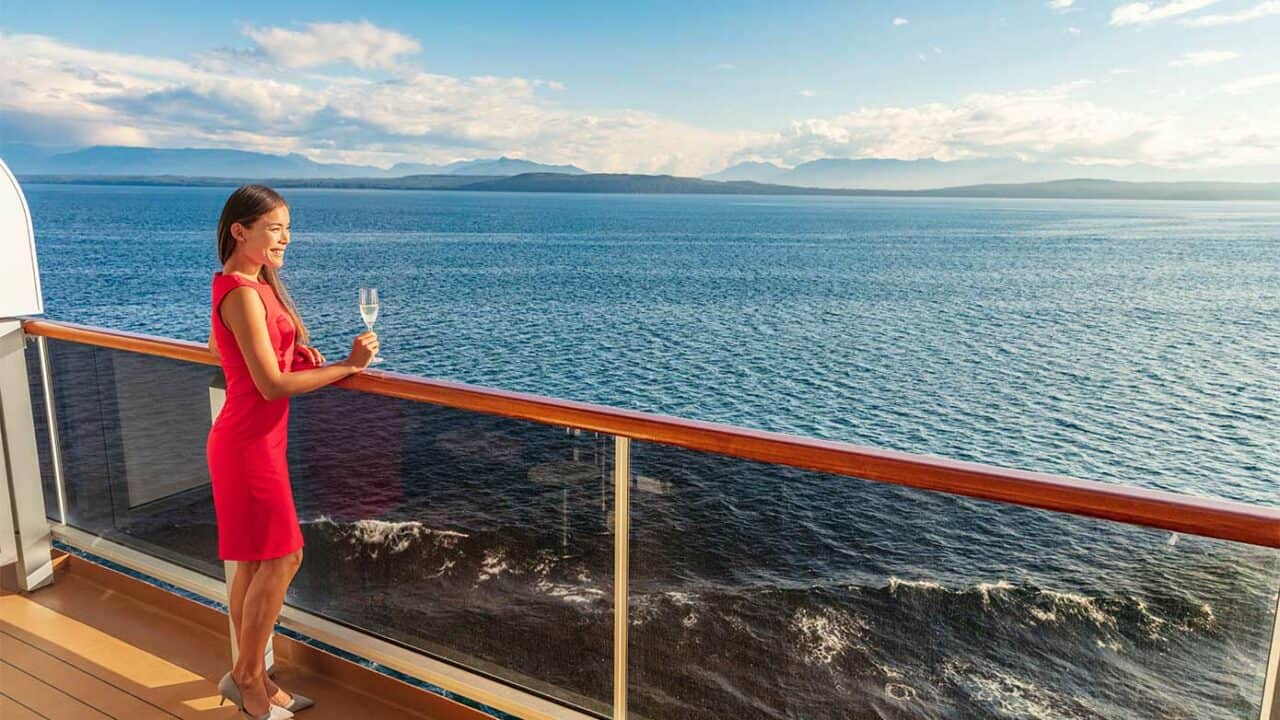 adult woman holding champagne on a cruise ship balcony.