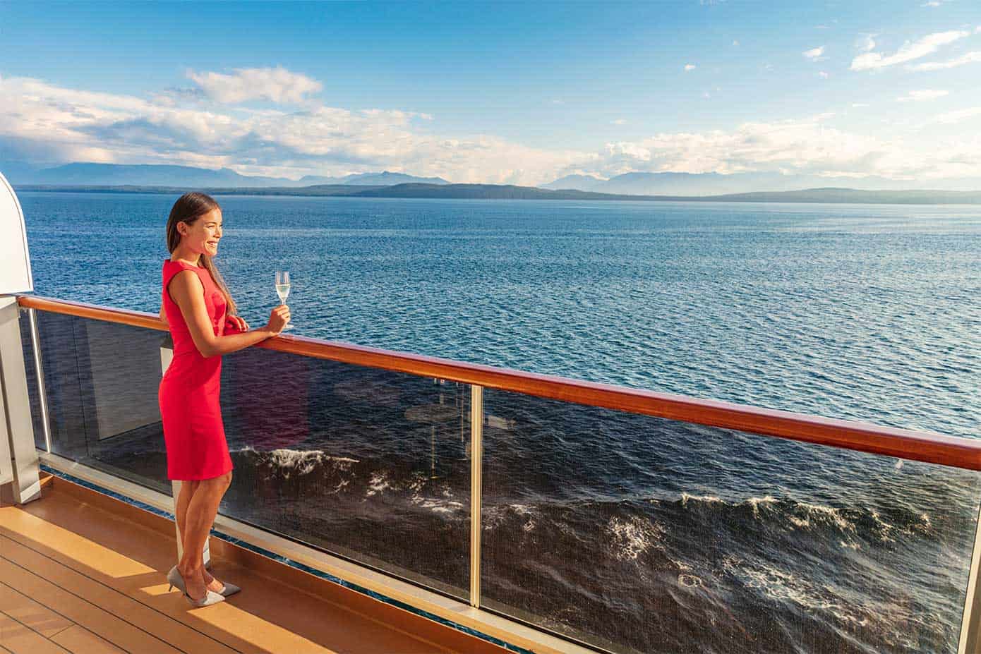 adult woman holding champagne on a cruise ship balcony.