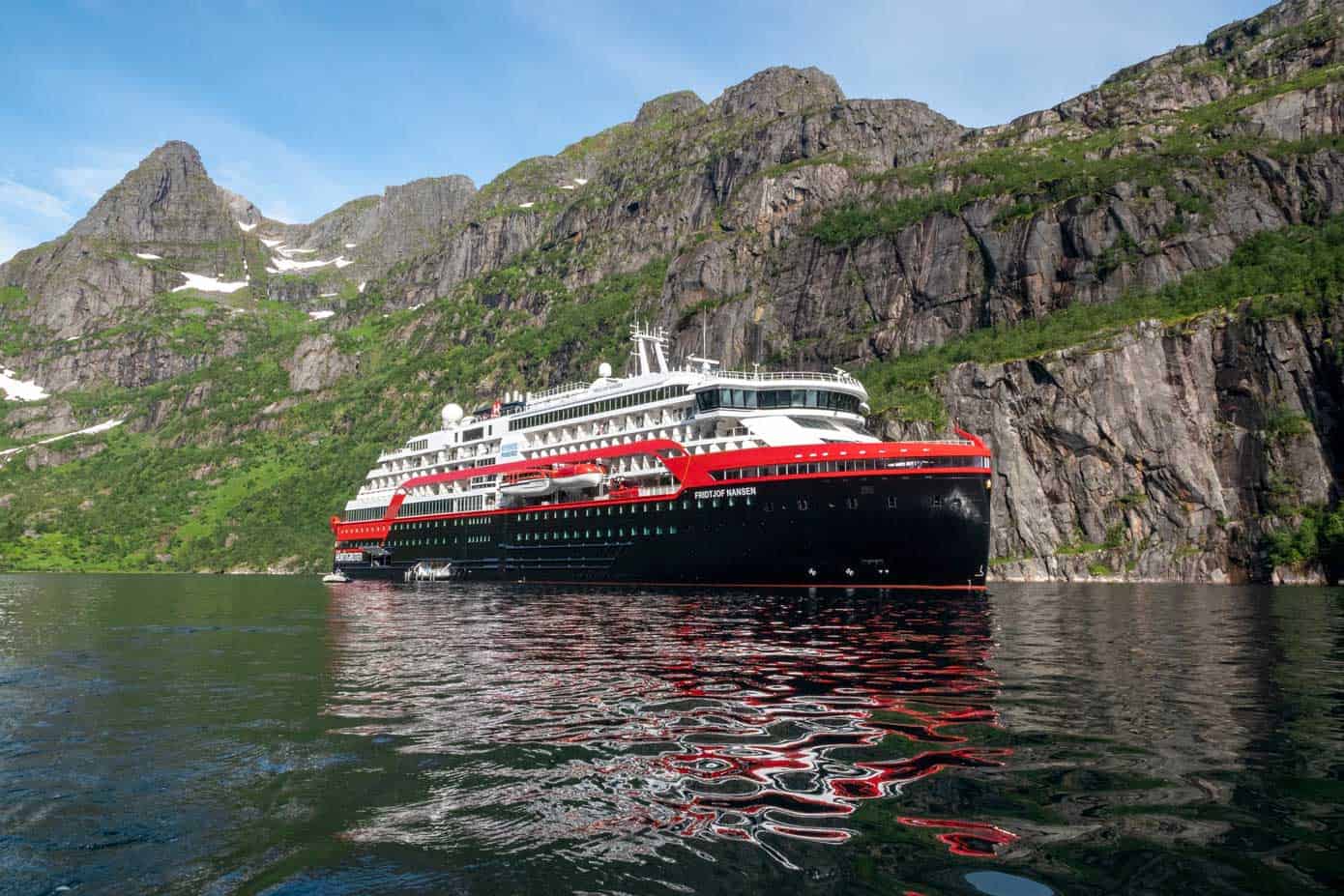 Cruise ship in the water with mountains in the background.