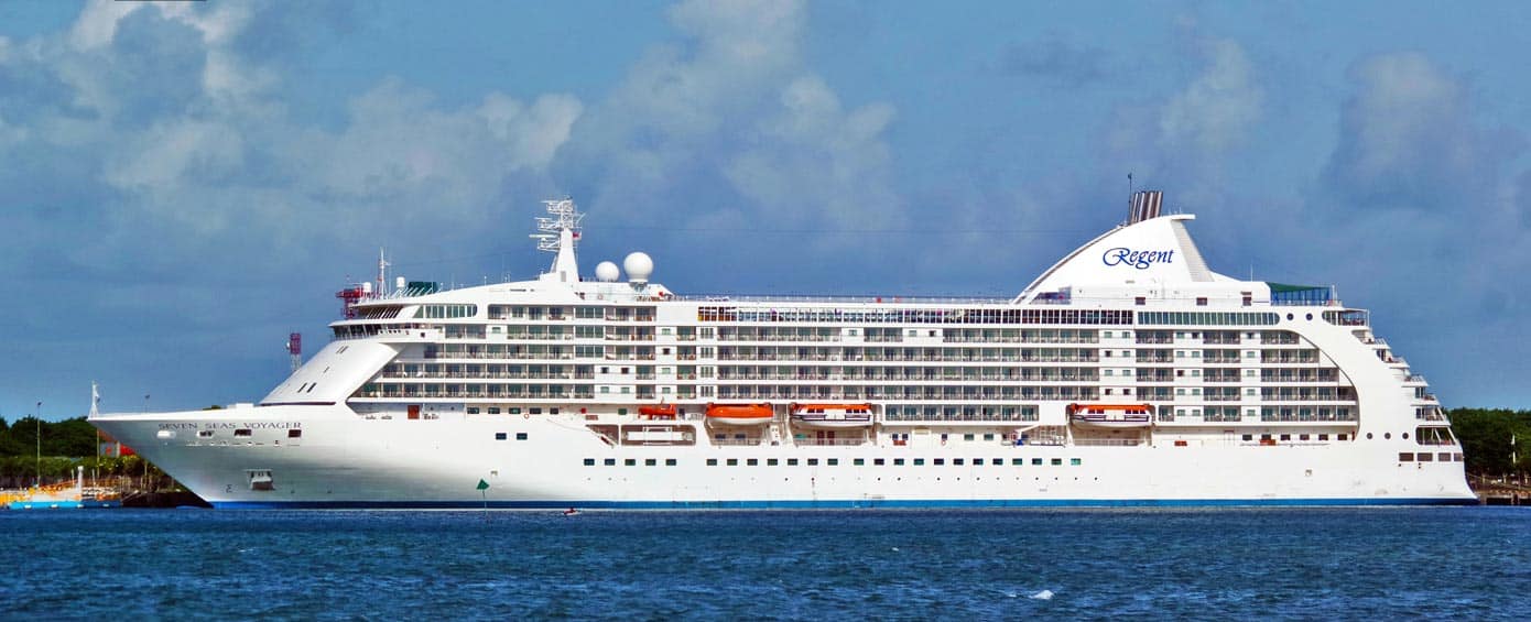 Full side view of a cruise ship sailing near land.