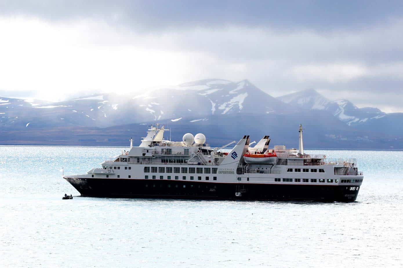 Cruise ship sailing in the ocean with icy mountains in the background.