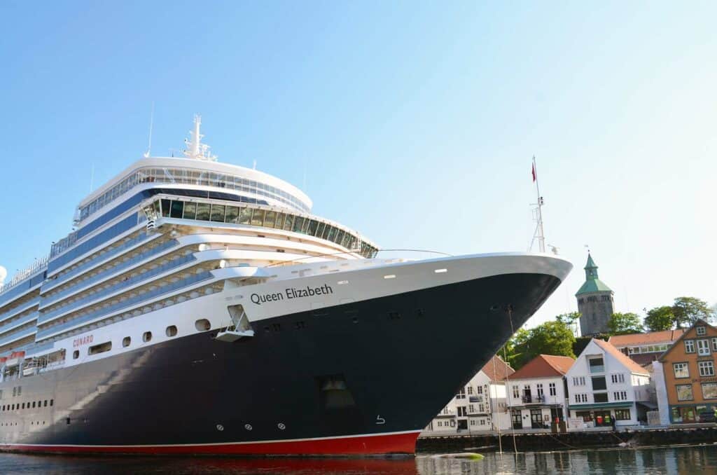 Cruise ship at port with historic city in background.