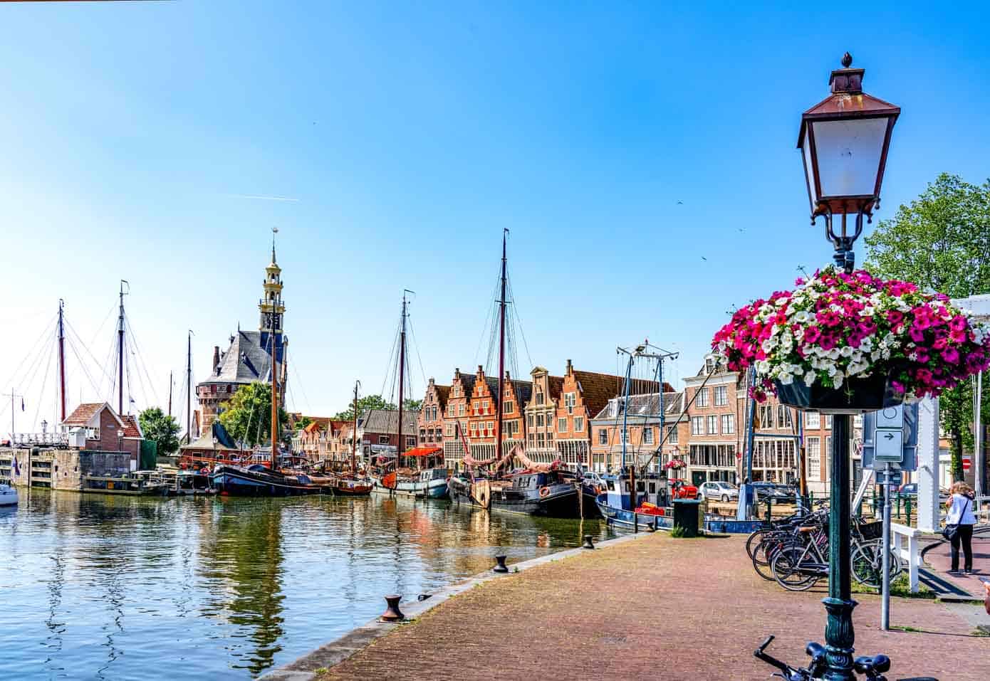 Walkway along the ocean with boats and old buildings in the background.