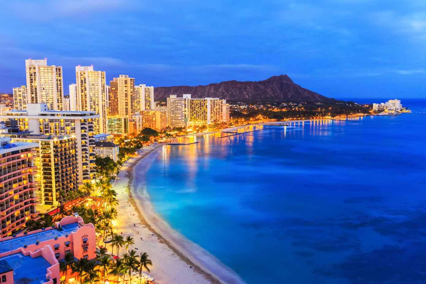 City on the beach at nighttime with mountains in the background.