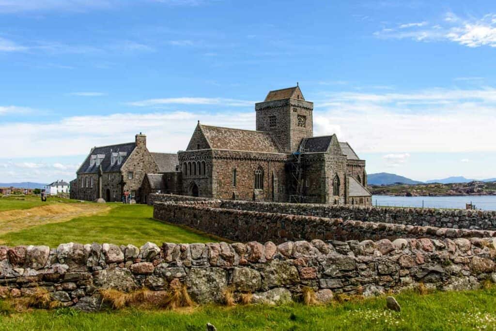 Historic abbey with rock walls and lush green grass just off the ocean.