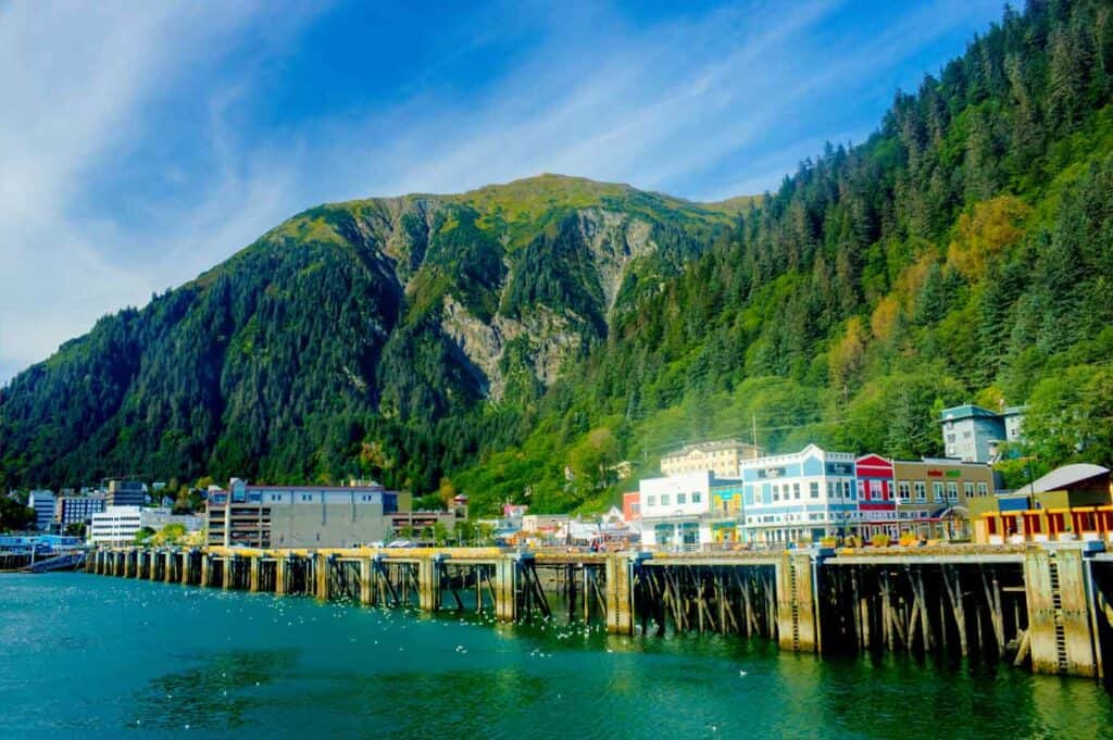 Dock on the ocean with lush mountains in background.