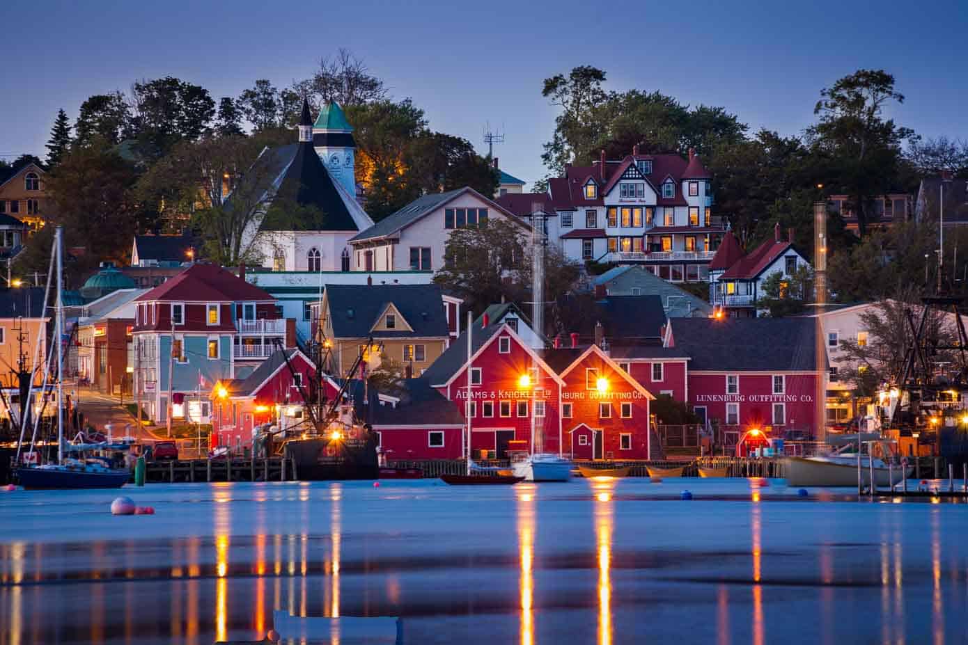 Historic buildings sit on a waterfront with many boats in Lunenburg, Nova Scotia.