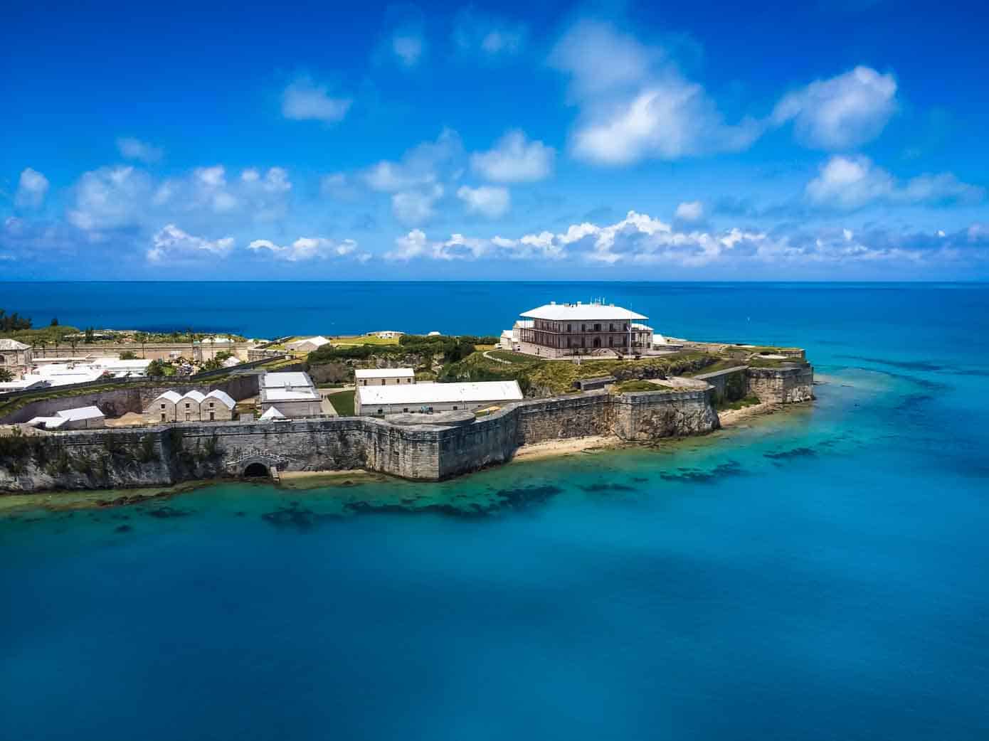 Best Time of Year to Cruise to Bermuda Old fortress called Royal Naval Dockyard in Bermuda jetting into a beautiful blue ocean.