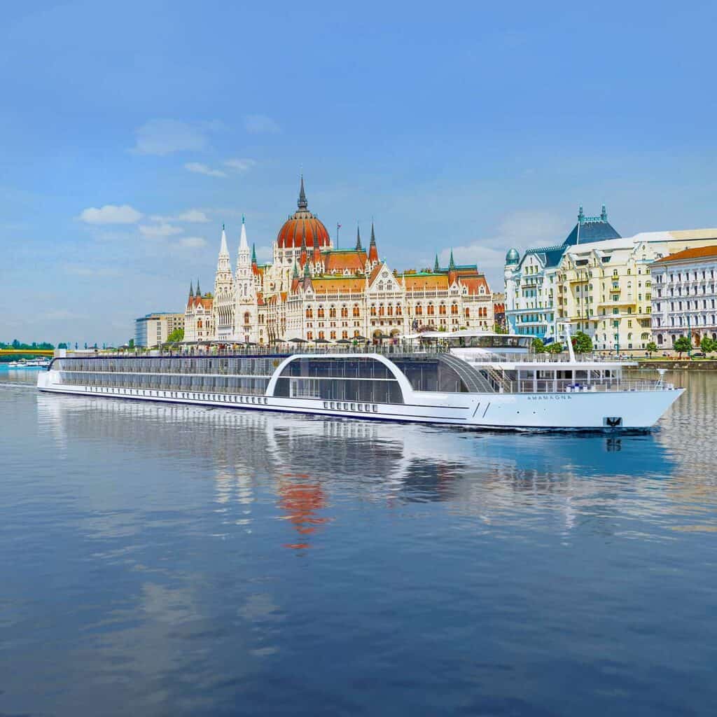 Exterior view of a river cruise ship with a historic city in the background.