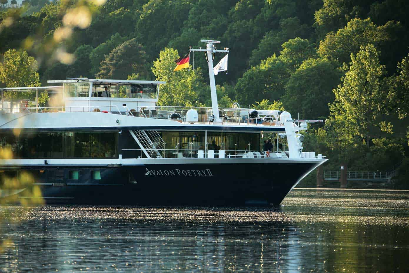 Front view of a river cruise ship with trees behind.