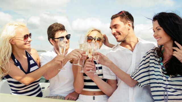 Group of adults celebrating and clinking glasses on a boat.