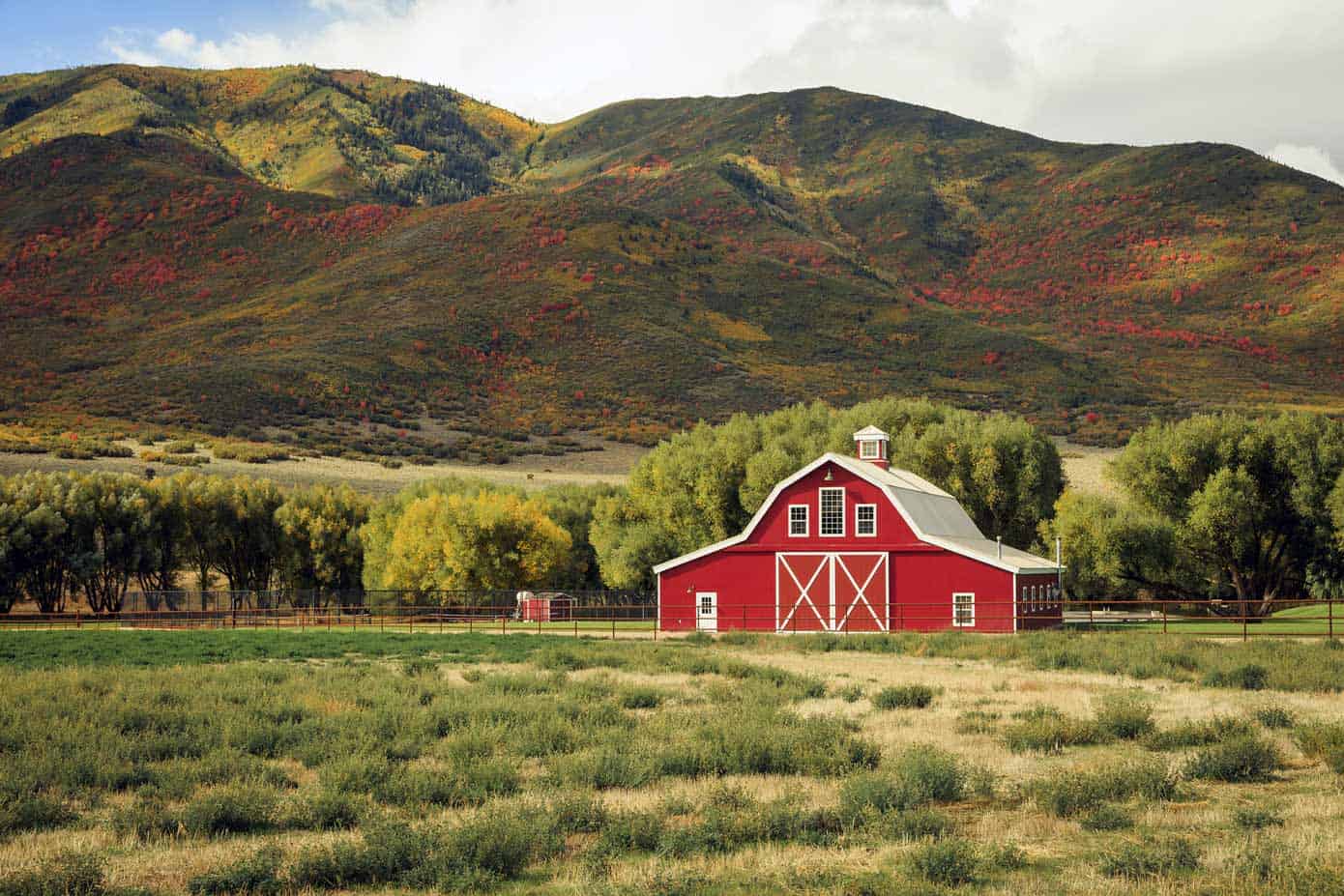 Picturesque red barn with rolling hills in the background.