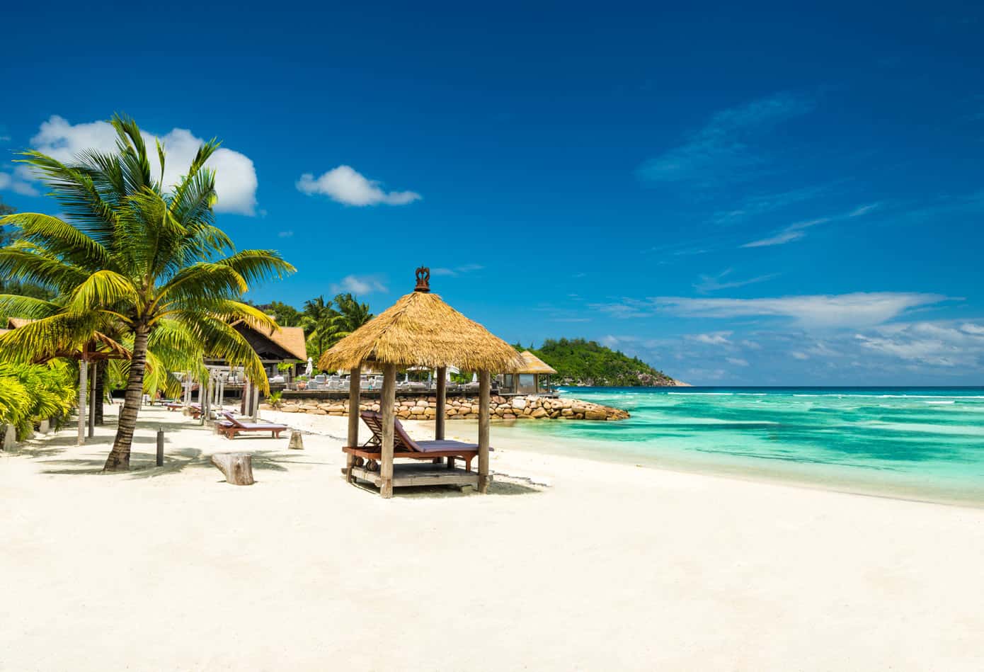 A sunny Caribbean beach with chairs, turquoise water and sapphire blue skies.