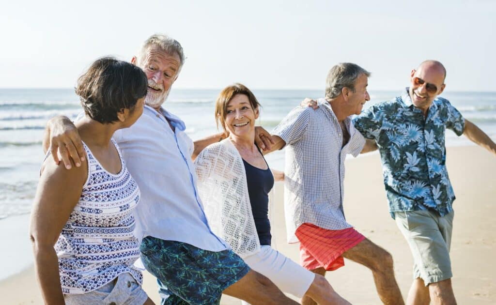 Group of older men and women celebrating on the beach.