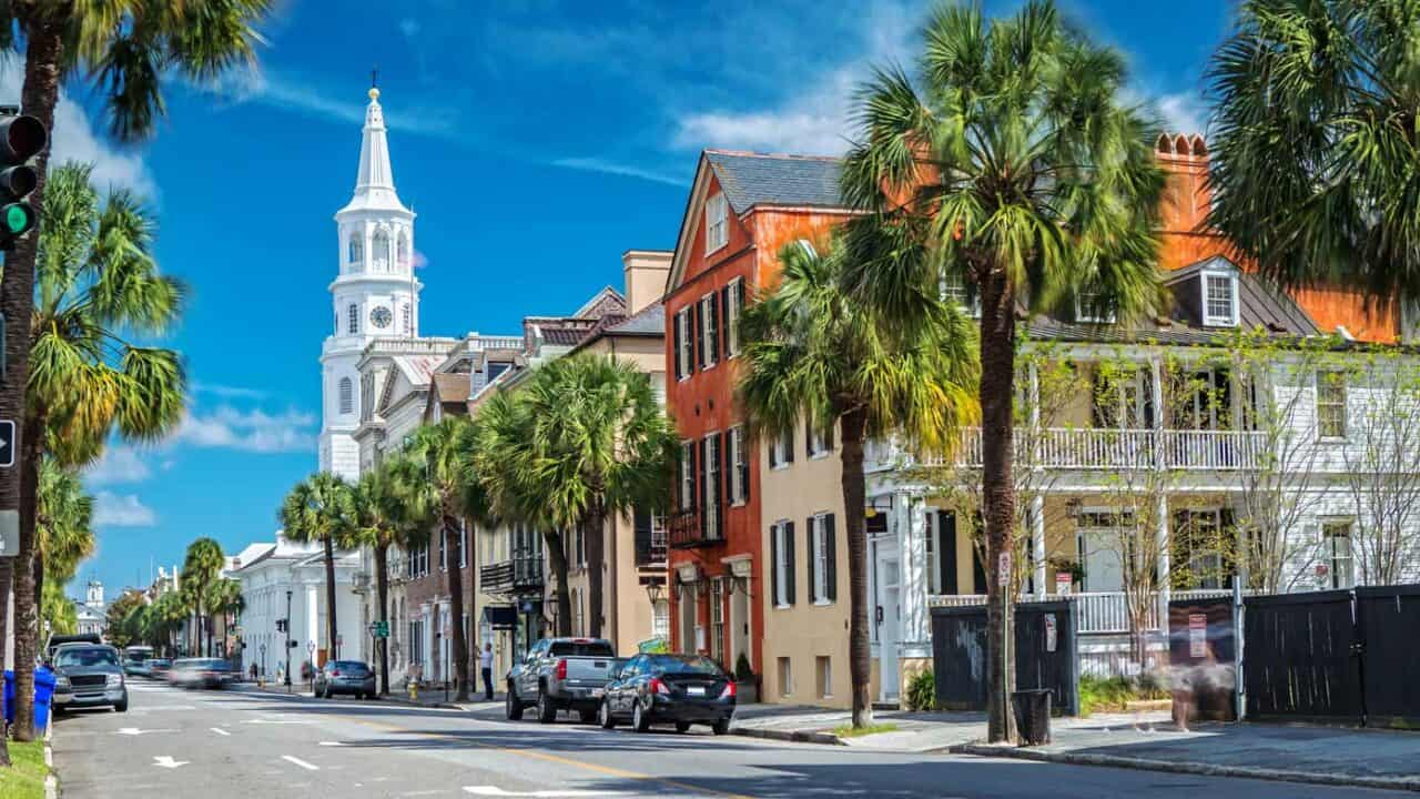 Historic city street in Charleston, South Carolina, lined with palm trees and Spanish style buildings.