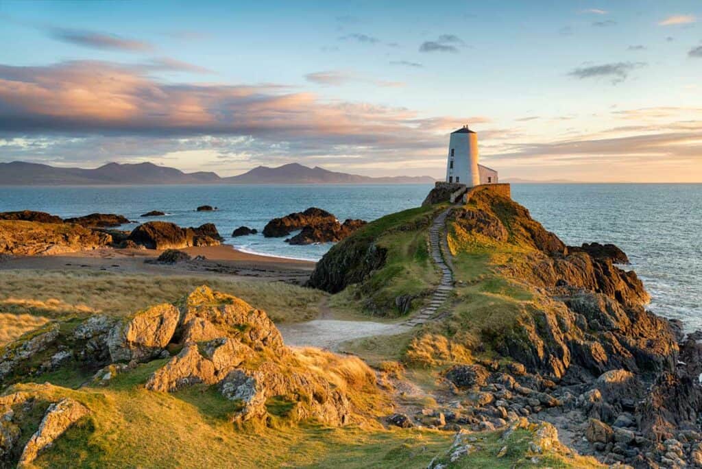 Rocky trail leading to a lighthouse on a cliff by the ocean in Wales.