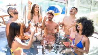 Group of young adults celebrating in a pool.