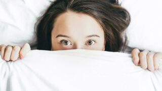 Woman peaking her head out from under the blanket.